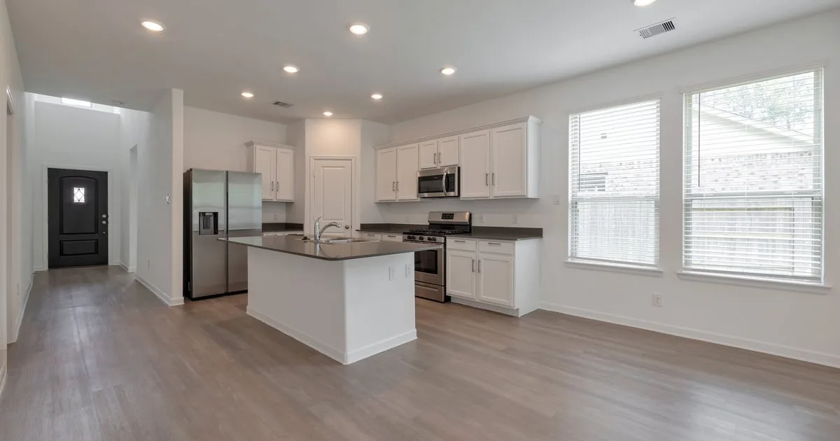 Empty modern Houston rental kitchen with white cabinets, stainless appliances, kitchen island, and hardwood flooring — Texas §92.103 30-day security deposit return move-out walkthrough landlord guide