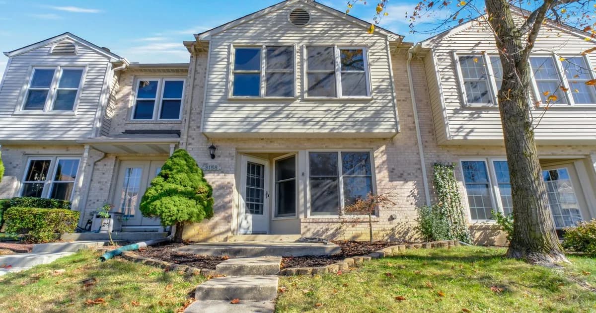 Single-family rental home on a quiet Frederick Maryland street in warm daylight — the Frederick County Public Schools attendance-zone stock that anchors demand from Fort Detrick and the NCI Frederick biotech base