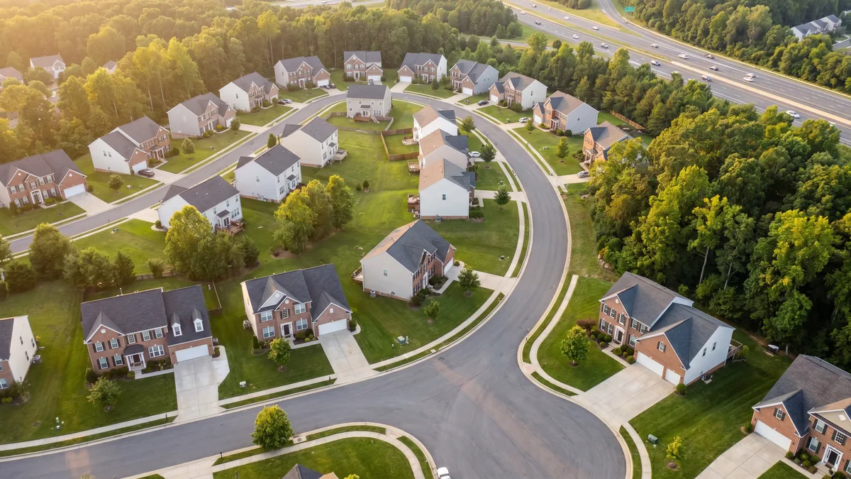 Aerial view of a newer single-family-home subdivision along the Fredericksburg / Stafford County I-95 commuter corridor with curving streets, cul-de-sacs, and wooded edges at golden hour