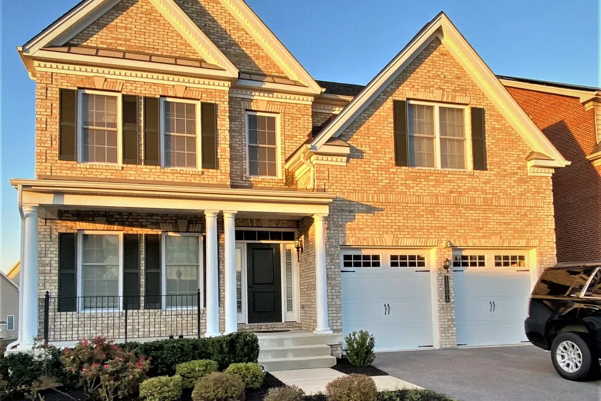 Brick colonial single-family rental home with a two-car garage and front porch in a Montgomery County, Maryland suburb — representative of the homes Flat Fee Landlord places tenants in across Maryland