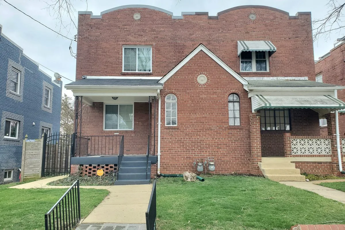 Brick rowhouse rental homes with covered front porches and bay fronts on a tree-lined Washington DC street