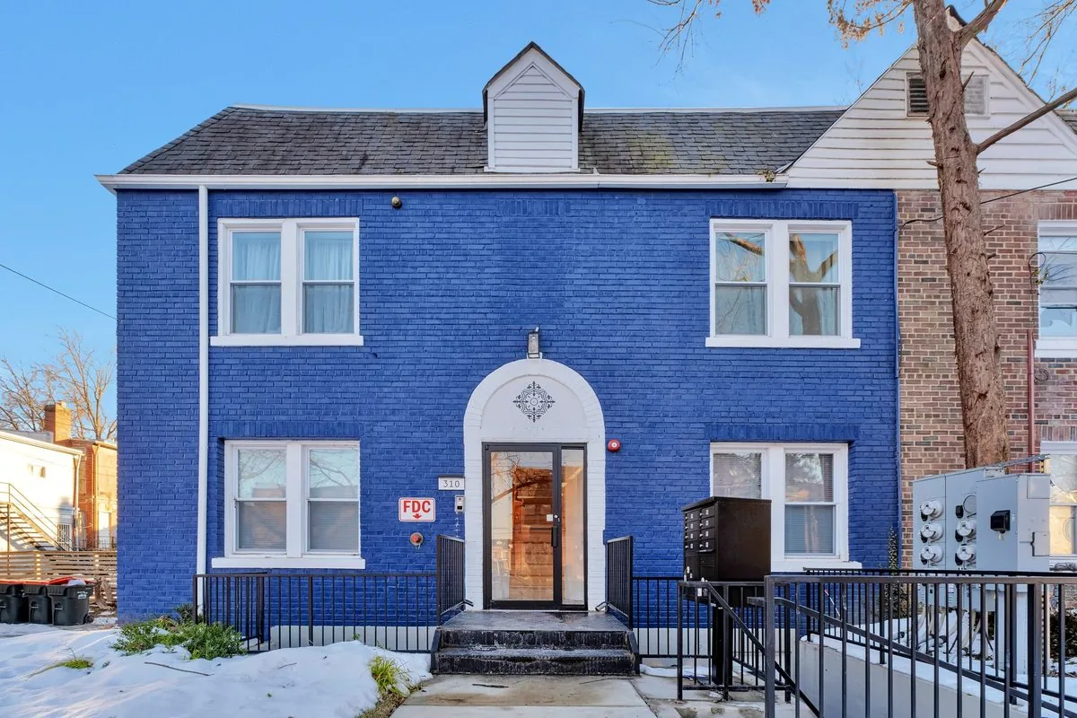 Blue-brick single-family rental home with white trim and a front stoop on a Washington DC residential street — representative of the rowhouses and condos Flat Fee Landlord places tenants in across the District
